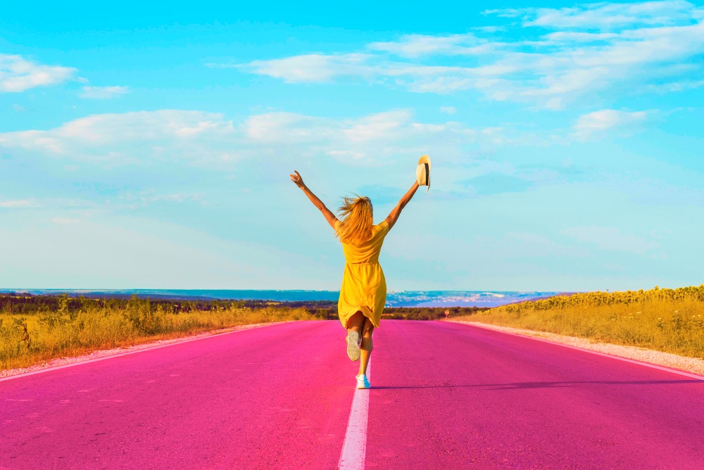Une femme heure qui saute sur une route rose