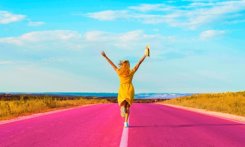 Une femme heure qui saute sur une route rose