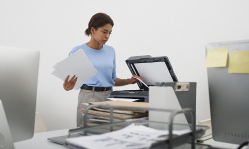 Faire appel à un prestataire certifié pour externaliser ses processus de numérisation est le meilleur moyen de se conformer aux réglementations. (Freepik) scanner-femme-travail-documents-imprimante
